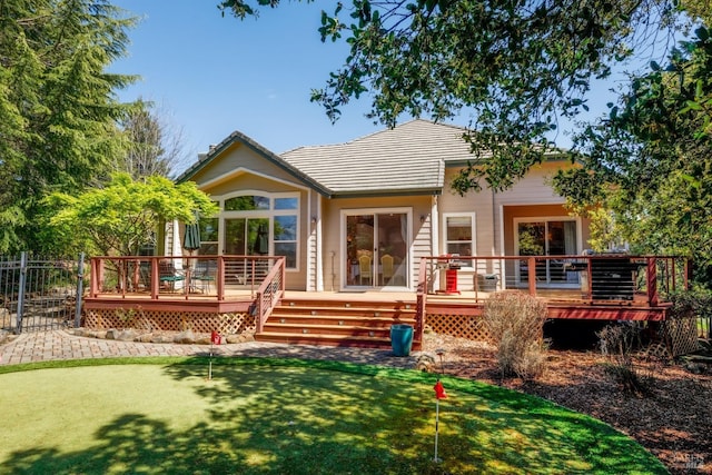 back of property with fence, a tile roof, and a deck