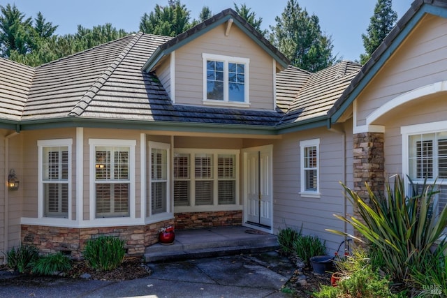 property entrance with stone siding and a tiled roof