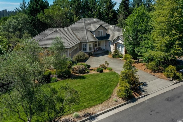 view of front of property featuring driveway, a tile roof, a garage, and a front yard