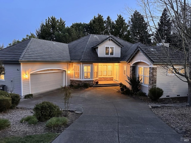 view of front of property with driveway, stone siding, a garage, and a tiled roof