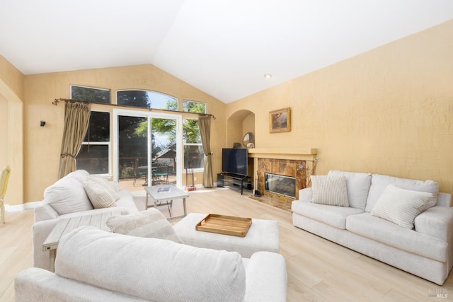 living area featuring arched walkways, wood finished floors, vaulted ceiling, and a premium fireplace