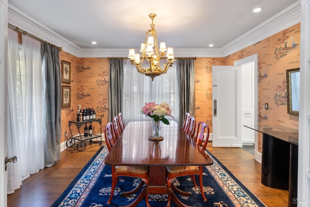 dining area with wallpapered walls, a notable chandelier, ornamental molding, and wood finished floors