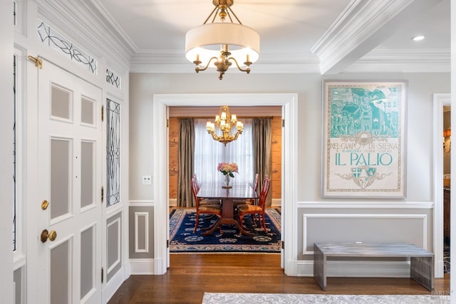 foyer with crown molding, a decorative wall, wood finished floors, and a notable chandelier