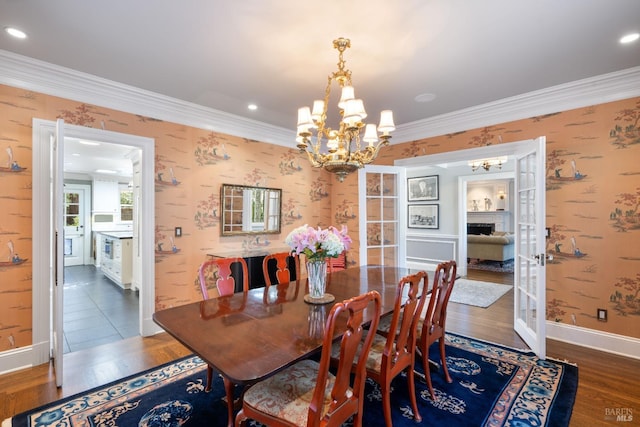 dining room featuring crown molding, wood finished floors, a notable chandelier, and wallpapered walls