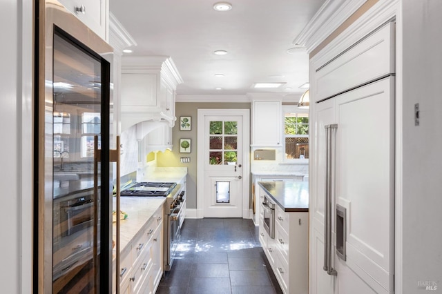 kitchen with ornamental molding, dark tile patterned floors, recessed lighting, white cabinets, and premium appliances