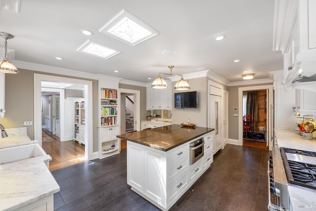 kitchen with ornamental molding, oven, white cabinets, a sink, and cooktop