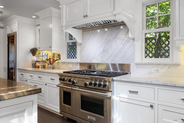 kitchen featuring recessed lighting, white cabinets, tasteful backsplash, custom range hood, and double oven range