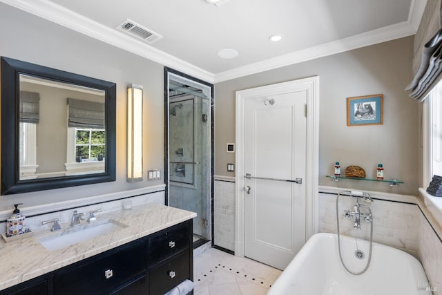 bathroom with crown molding, tile patterned flooring, vanity, a freestanding tub, and tile walls