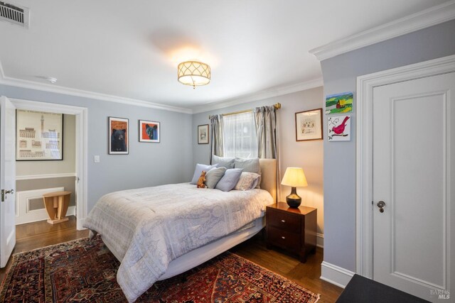 bedroom with baseboards, dark wood finished floors, ornamental molding, and visible vents