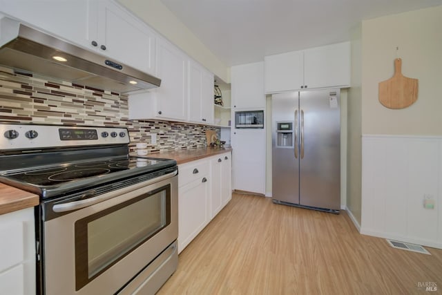 kitchen featuring light wood finished floors, white cabinets, under cabinet range hood, and appliances with stainless steel finishes