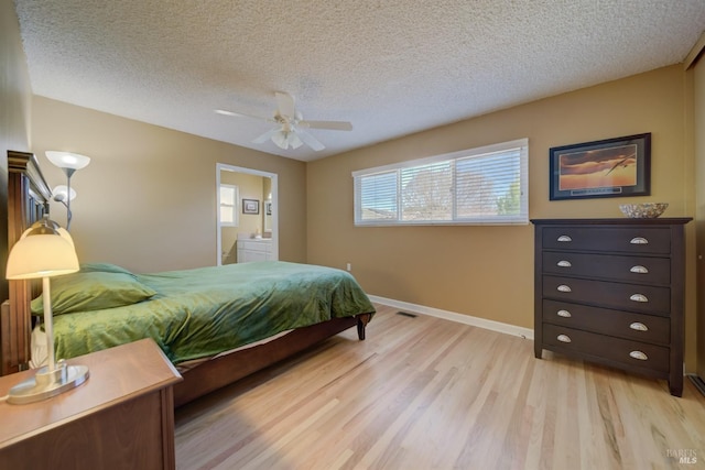 bedroom with a ceiling fan, a textured ceiling, light wood-type flooring, ensuite bathroom, and baseboards