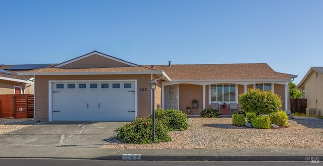 ranch-style house featuring fence, driveway, an attached garage, and central AC