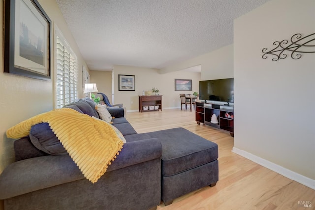 living room featuring baseboards, light wood-type flooring, and a textured ceiling