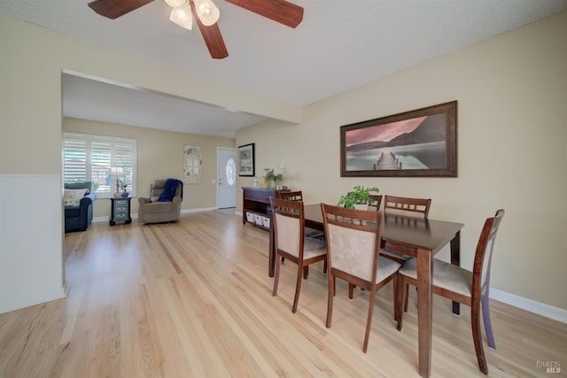dining room featuring a textured ceiling, baseboards, light wood-style floors, and a ceiling fan