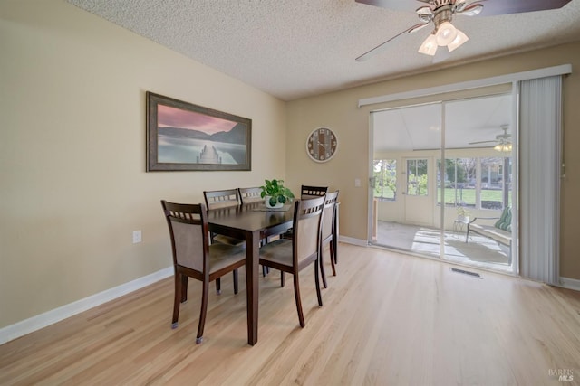 dining room with light wood-style flooring, baseboards, a textured ceiling, visible vents, and a ceiling fan