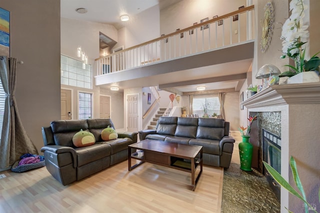 living room with a high ceiling, wood finished floors, stairs, and a fireplace