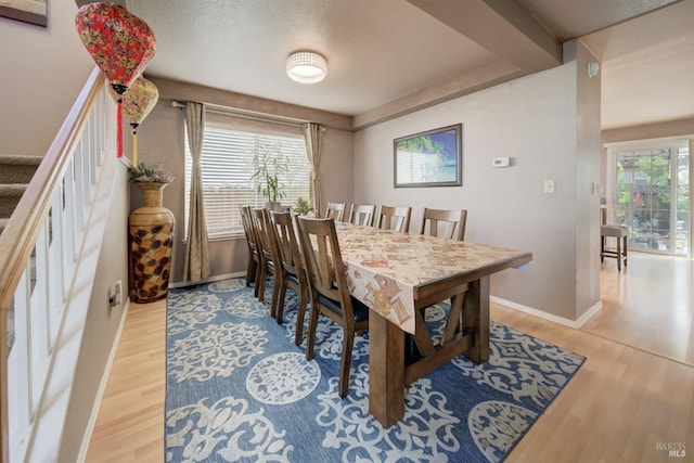 dining space with stairway, baseboards, and wood finished floors