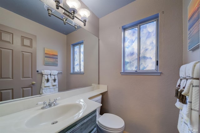 half bath with toilet, vanity, and an inviting chandelier