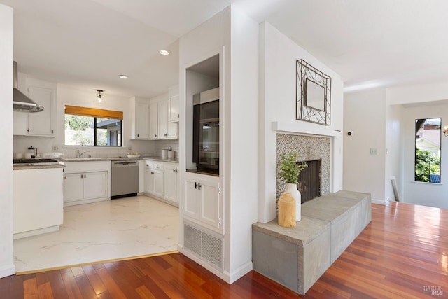 kitchen with recessed lighting, a tile fireplace, white cabinets, dishwasher, and visible vents