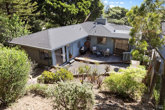back of property with fence, a chimney, a shingled roof, and a wooden deck