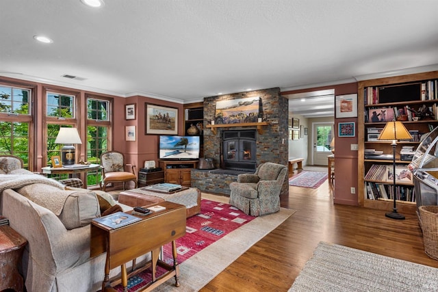 living room featuring recessed lighting, wood finished floors, visible vents, ornamental molding, and a fireplace