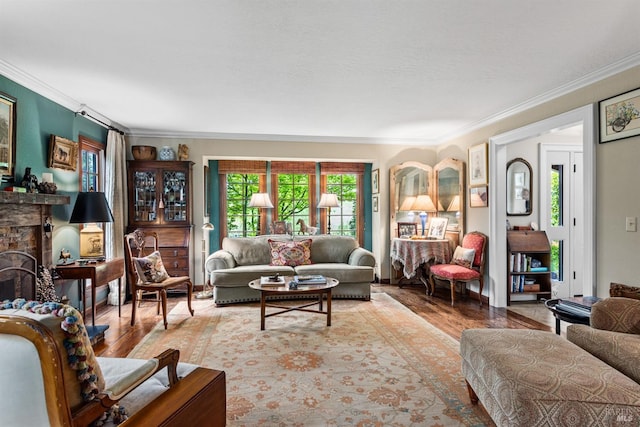living room featuring wood finished floors, crown molding, and a stone fireplace