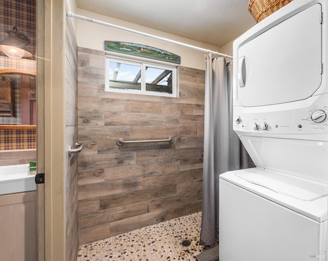 laundry area with laundry area, stacked washing maching and dryer, and wooden walls
