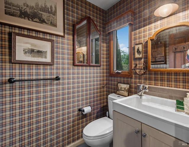 bathroom with wallpapered walls, toilet, and vanity