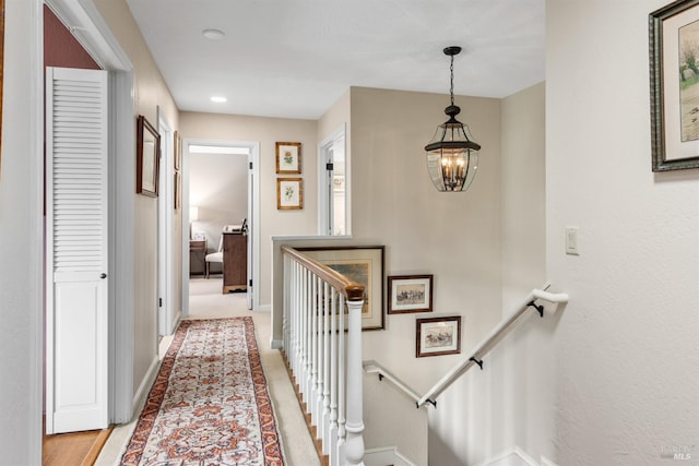 hall featuring recessed lighting, an inviting chandelier, baseboards, and an upstairs landing