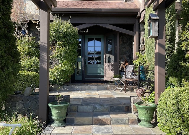 view of exterior entry with stone siding and a patio