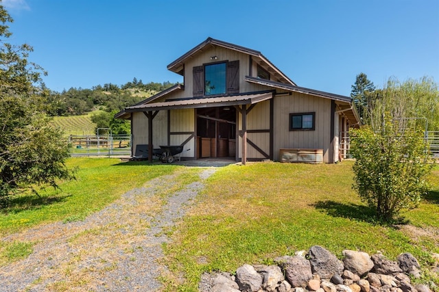 back of property featuring an outdoor structure, fence, and a yard