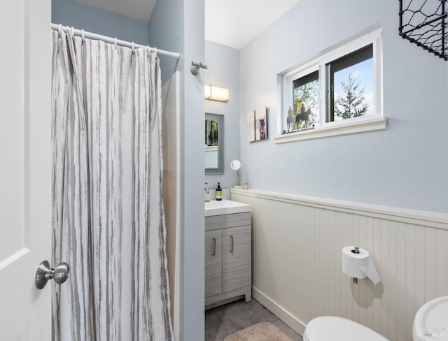 full bathroom with toilet, a shower with curtain, vanity, and a wainscoted wall