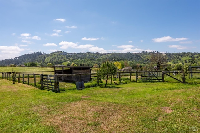 view of yard with a rural view, an outbuilding, a mountain view, and an exterior structure