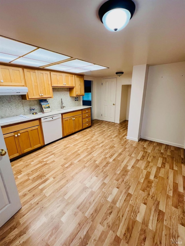 kitchen featuring light wood finished floors, white dishwasher, light countertops, and tasteful backsplash