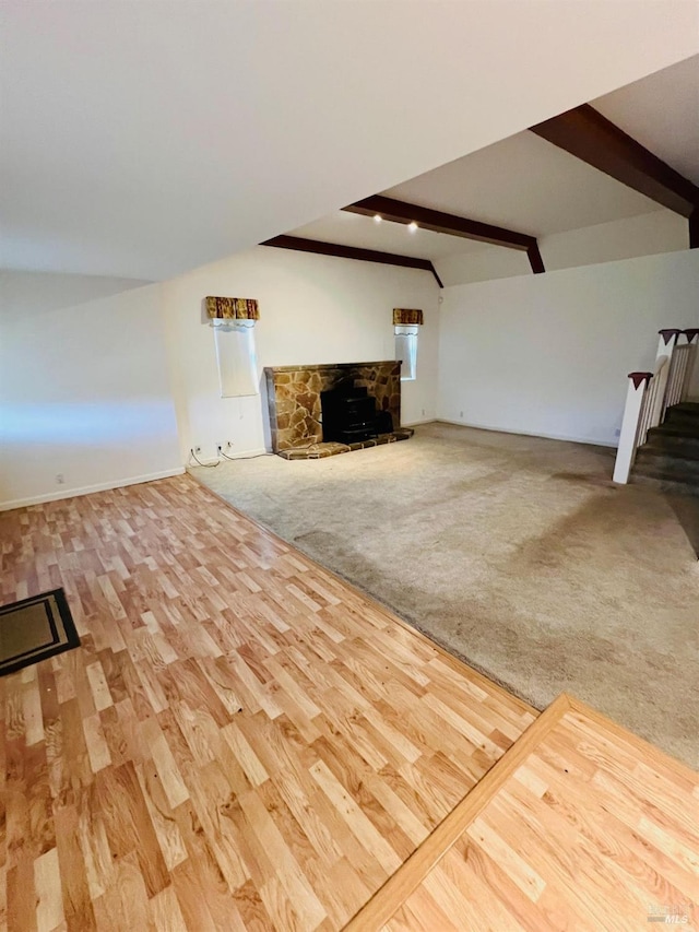 unfurnished living room with stairs, wood finished floors, vaulted ceiling with beams, and carpet flooring
