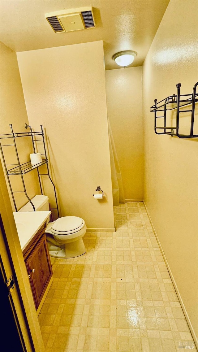bathroom featuring toilet, tile patterned floors, baseboards, and visible vents