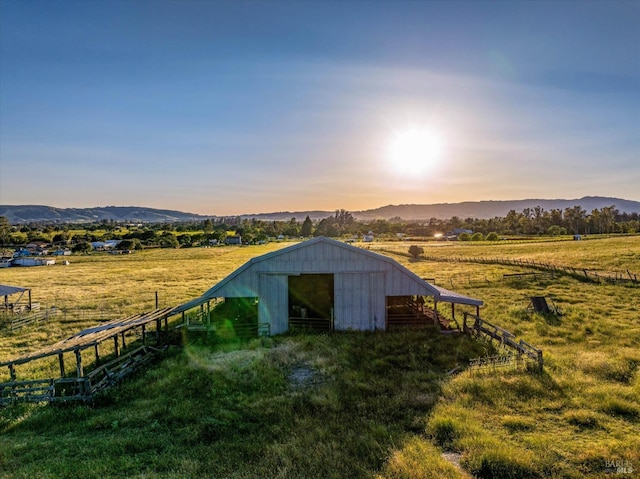 view of outbuilding featuring an outdoor structure, a mountain view, fence, and a rural view
