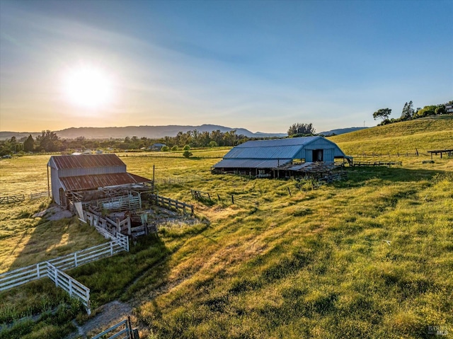 yard at dusk featuring an outbuilding, fence, and a rural view