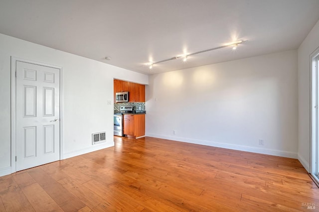 unfurnished living room featuring baseboards, visible vents, and light wood-type flooring