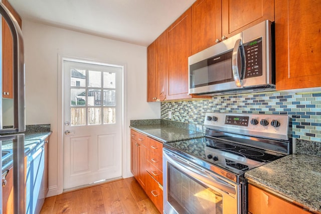 kitchen with brown cabinets, light wood-type flooring, tasteful backsplash, and stainless steel appliances