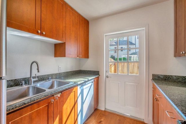 kitchen featuring dishwasher, light wood-type flooring, a sink, and brown cabinets