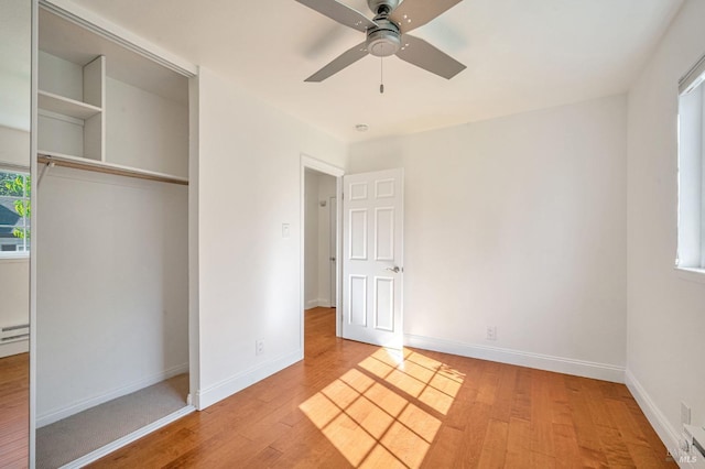unfurnished bedroom featuring a closet, light wood-style flooring, baseboards, ceiling fan, and baseboard heating