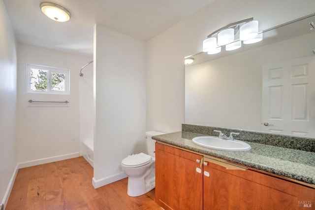 full bathroom featuring toilet, vanity,  shower combination, wood finished floors, and baseboards