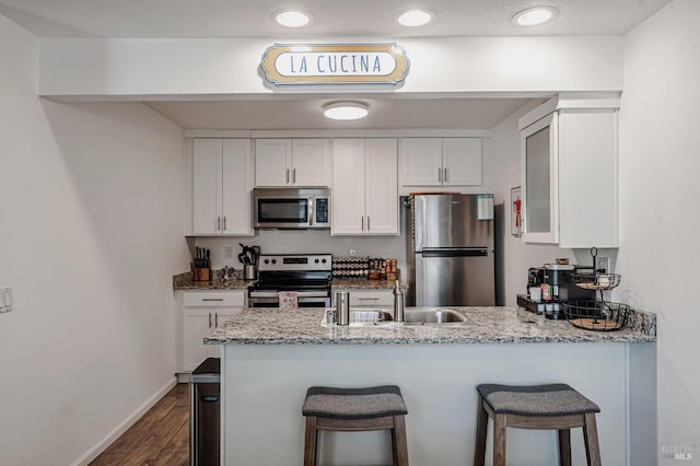 6482 Meadow Pines Ave, Rohnert Park, CA 94928 - kitchen with stainless steel appliances, a sink, light stone counters, white cabinets, and a peninsula