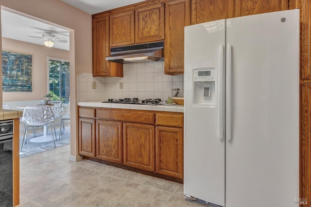 271 Antigua Way, Vallejo, CA 94591 - kitchen featuring white refrigerator with ice dispenser, under cabinet range hood, brown cabinetry, tasteful backsplash, and a ceiling fan