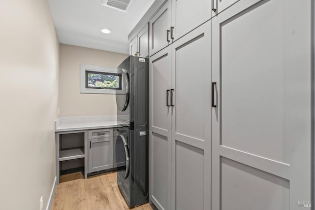 1108 Raymond Ave, Napa, CA 94559 - clothes washing area with light wood-style flooring, visible vents, stacked washing maching and dryer, baseboards, and cabinet space