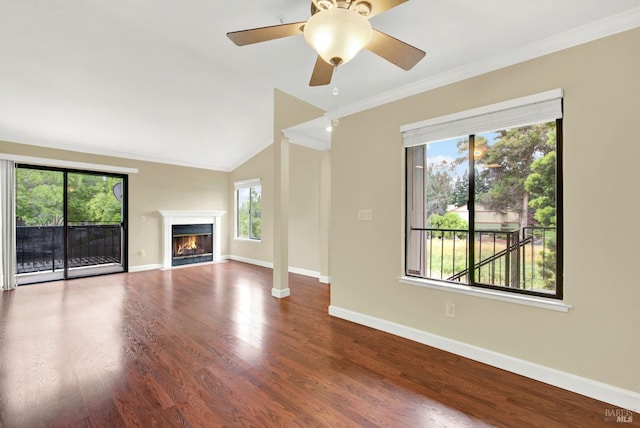 unfurnished living room with vaulted ceiling, baseboards, wood finished floors, crown molding, and a lit fireplace