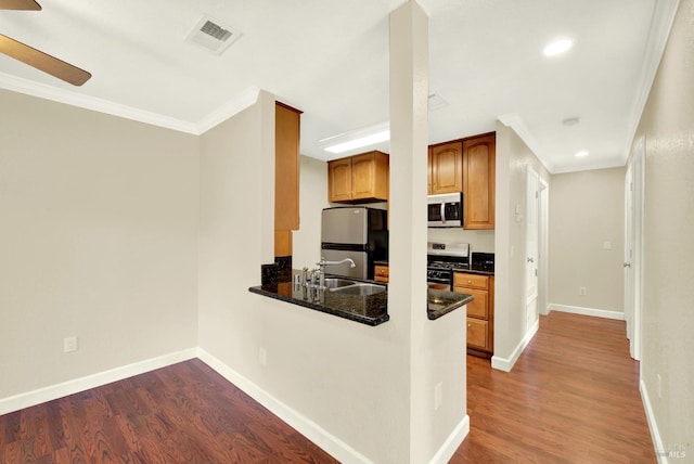 kitchen featuring dark wood finished floors, visible vents, ornamental molding, a sink, and appliances with stainless steel finishes