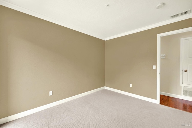 carpeted spare room with visible vents, crown molding, and baseboards