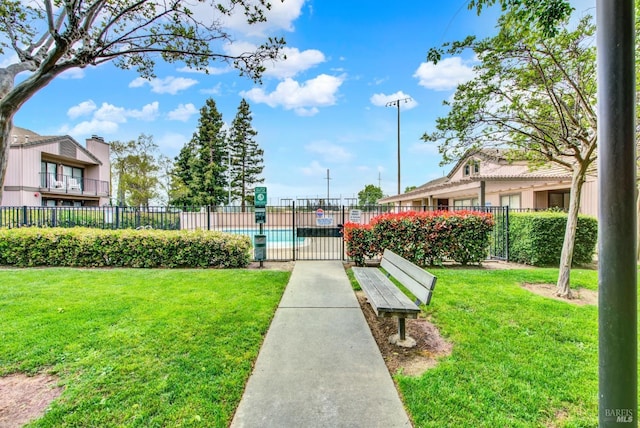 view of community featuring fence and a yard
